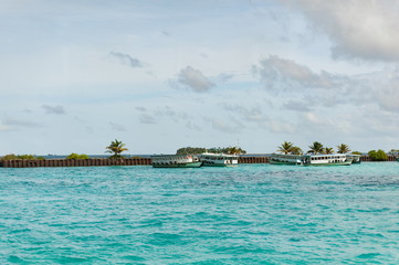 Obraz premium Tropical wharf with boats in Maldives in Indian Ocean. Ships on the water. Piece of paradise on the Earth. Good choice for vacation. Beautiful view for wallpaper.