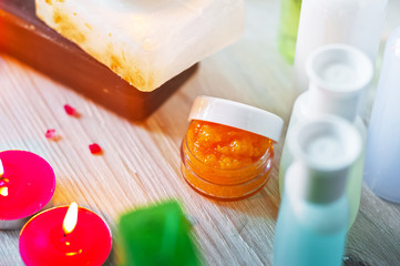 Spa accessories. Small lighted candles, many colored soaps of soap, many different shapes of bottles for the bathroom. The bath salt is pink, the body scrub is showered. Light brick and white wooden a