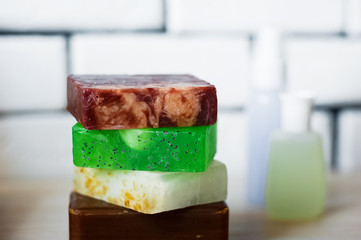 Spa accessories. Sprigs of a Christmas tree, many multi-colored pieces of soap, many different shapes of bottles for a bathroom. Body scrub. Light brick and white wooden as a background