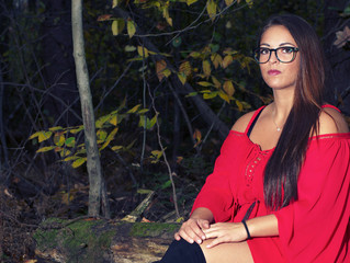 young women stiting in the forest wearing red dress and glasses