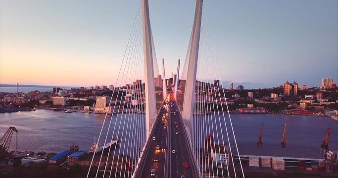 Slowly descending above the Golden Bridge (built in 2012) with cars driving across it. It's cable-stayed bridge across the Zolotoy Rog harbour. Evening. Aerial view. Vladivostok city, Russia