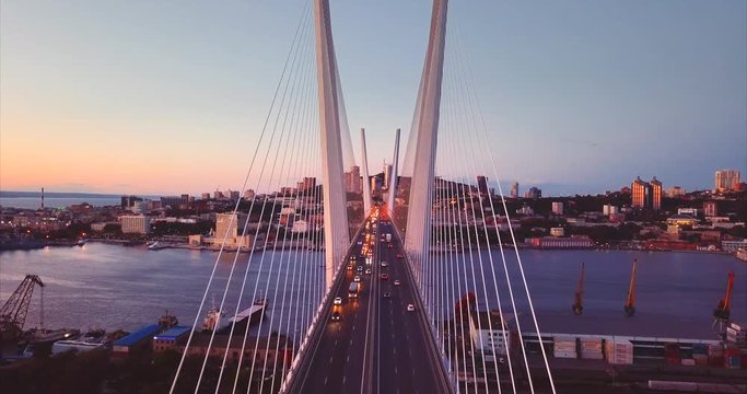 Aerial static view of Golden Bridge (built in 2012) with cars driving across it. It's cable-stayed bridge across the Zolotoy Rog harbour. Evening. Vladivostok city, Russia