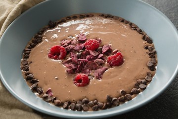 Chocolate syrup with fruits in bowl on black background