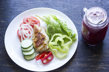 A fresh meal of chicken fillet with vegetables and tasty juice on a dark wooden background