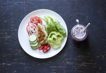 A fresh meal of chicken fillet with vegetables and tasty juice on a dark wooden background