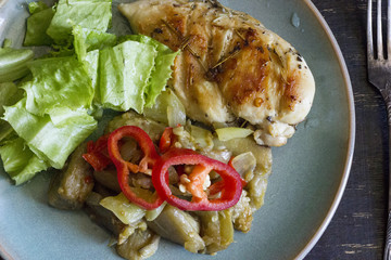 A fresh meal of chicken fillet with vegetables and tasty juice on a dark wooden background