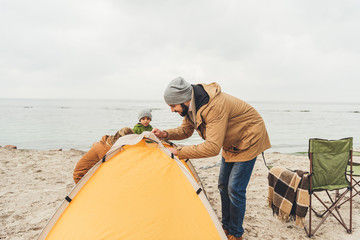 man intalling camping tent on seahore