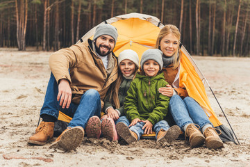 family sitting next to camping tent