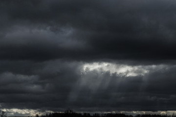 the sun shines through the black clouds. rain.