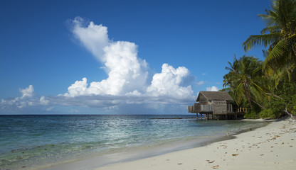 Tropical beach. Ocean waves and cloudy sky background. White sand and crystal-blue sea. Ocean water nature, beach relax. Summer sea vacation. Maldives islands sea background