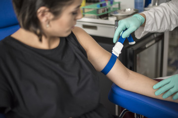 infermiere stringe laccio emostatico prima di eseguire un'analisi del sangue