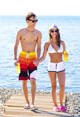 Jolly youthful couple enjoying summer drinks on resort