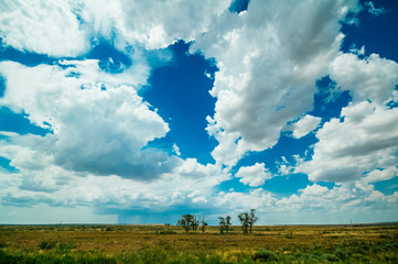 The plains of northern Texas under a blue sky, with a storm in the distance.