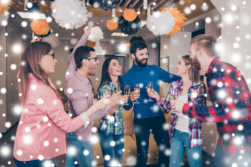 Happy cheerful student's team having party with champagne. Snowflakes background