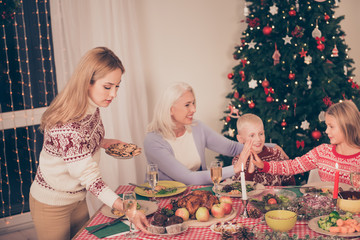 Cheerful relatives, setted festive desktop, full of yummy treats, apples, vegetables, cheerful siblings, granny, mom, decorated pine firtree, lights on windows, bon appetite!