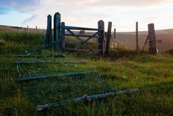 A fallen farm fence next to a gate.