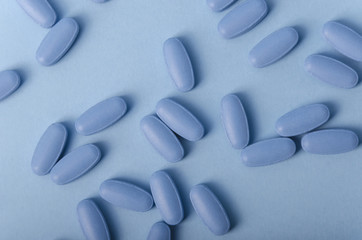 random composition of blue tablets over a light blue background for medical uses.