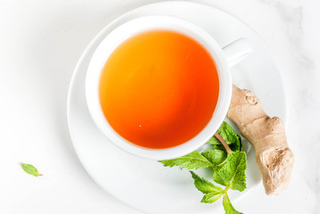 Cup of ginger tea with lemon,fresh mint and honey, on white marble table, copy space top view