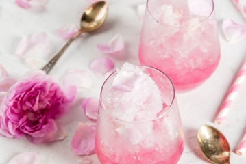 Summer refreshing desserts. Vegan diet food. Ice cream frozen rose, froze, with rose petals and rose wine. On a white concrete table, with spoons, striped straws, petals and rose flowers. Copy space