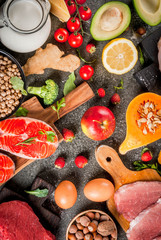 Healthy diet background. Organic food ingredients, superfoods: beef and pork meat, chicken filet, salmon fish, beans, nuts, milk, eggs, fruits, vegetables. Black stone table, copy space top view