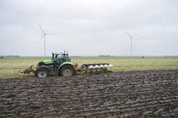 freshly plowed land and tractor with plough in dutch field end of autumn in the neth