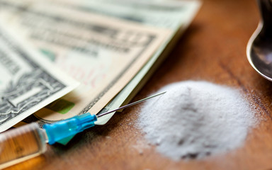 Money, drug, spoon and syringe with heroine on a table
