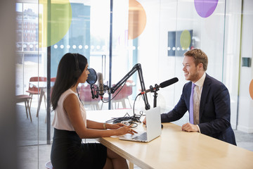 Young woman interviewing a guest in a studio for a podcast - obrazy, fototapety, plakaty