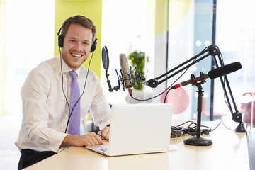 Young man recording a podcast smiling to camera, close up