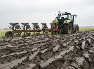 freshly plowed land and tractor with plough in dutch field end of autumn in the neth