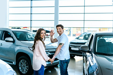 Man waving hand in car showroom