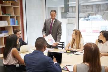 Male boss holding document at a business boardroom meeting