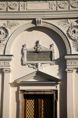 gray richly carved and decorated tombstone surrounded by greenery and warm sunshine shining from behind the trees