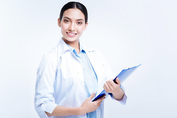 Pretty doctor holding blue sheet holder and smiling