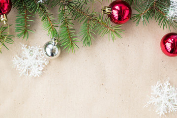 Festive christmas border with red and silver balls on fir branches and snowflakes on rustic beige background