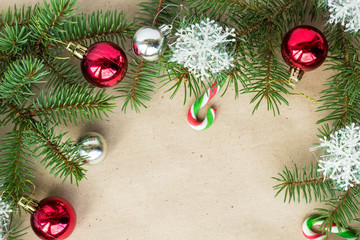 Festive christmas border with red and silver balls on fir branches and snowflakes on rustic beige background