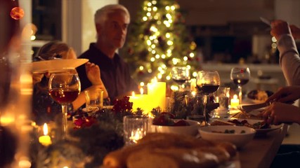 Christmas eve dinner, family sitting at dining table enjoying dinner together. Family celebrating christmas together at home. - Powered by Adobe