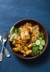 Deep-fried fish and garlic baked potatoes on a blue background, top view. Fish and chips. Street, takeaway food