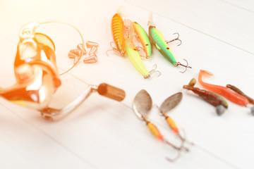 Fishing rod with reel, spoon baits, tackles and wobblers in box for catching or fishing a predatory fish on white vintage wooden background