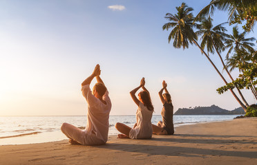 People practicing yoga on the beach, wellbeing, warm tropical landscape