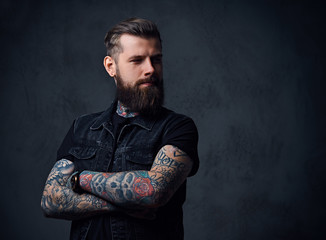 Studio portrait of bearded hipster male with tattoos on his arms