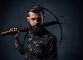 A man dressed in a military jacket holds crossbow.