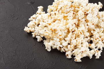 Popcorn horizontal banner. Red stripped paper cup and kernels lying on dark background. Copy space.