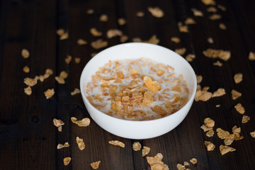 Corn flakes with milk on a wooden background