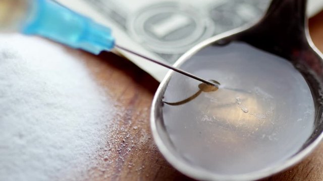 Money, drug, spoon and syringe with heroine on a table. 4K UltraHD video footage