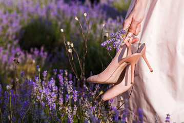  girl holds shoes in hand in lavender field