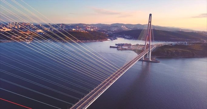 Flying backwards above the Russian Bridge, the world's longest cable-stayed bridge built across the Eastern Bosphorus strait. Russian island and Vladivostok are on the background. Aerial. Russia