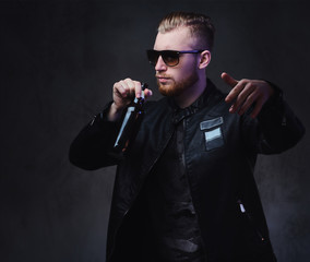 Bearded male holds a bottle with craft beer.