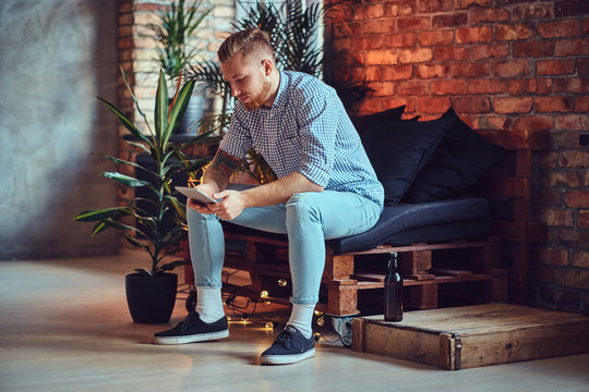 The full body image of blond stylish male using a tablet PC.