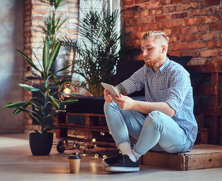 The full body image of blond stylish male using a tablet PC.