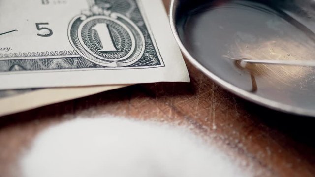 Money, drug, spoon and syringe with heroine on a table. 4K UltraHD video footage